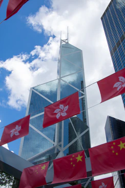 A group of flags flying in the wind in front of a tall building