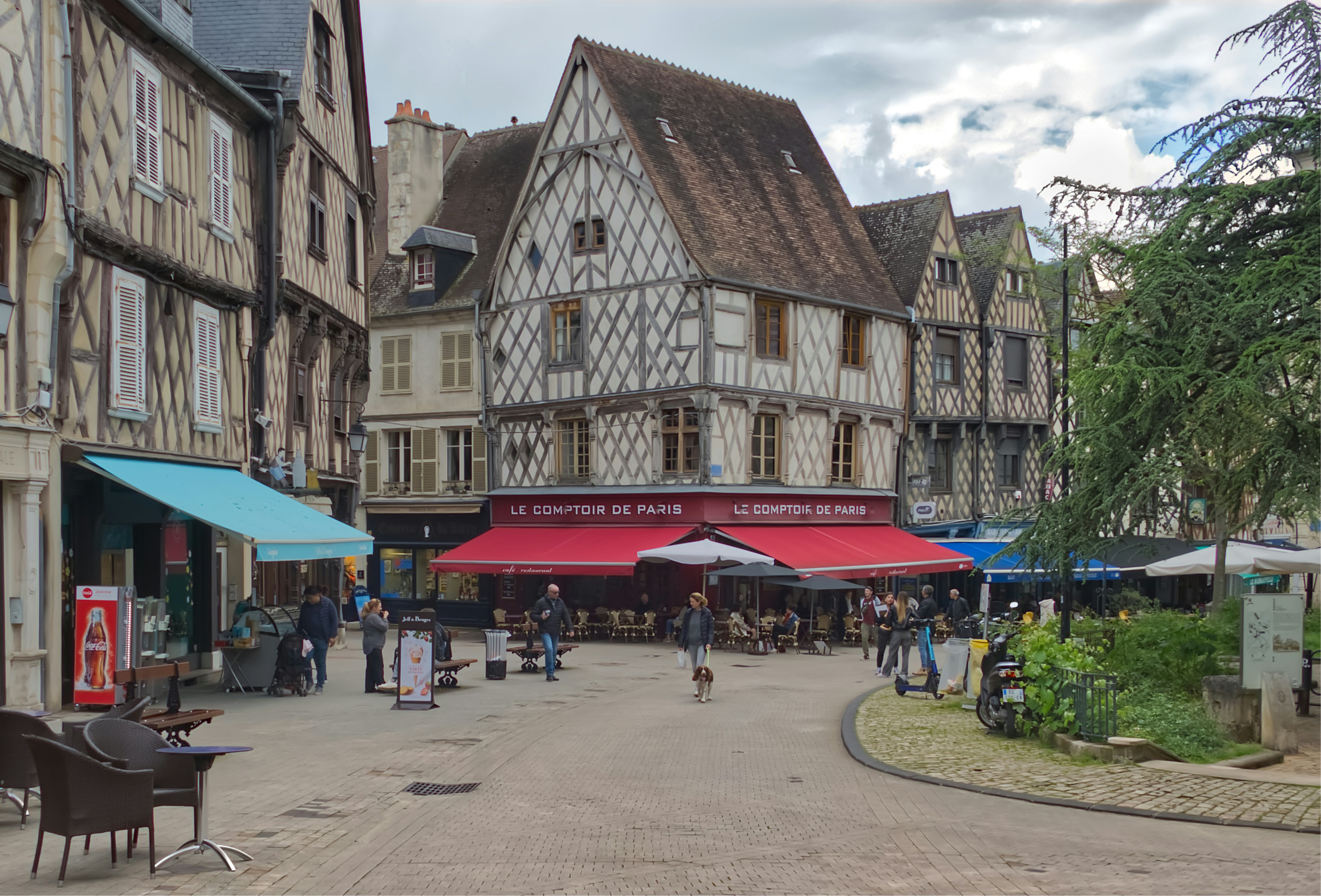 A group of people walking down a street next to tall buildings