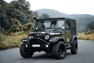 A black jeep driving down a rural road