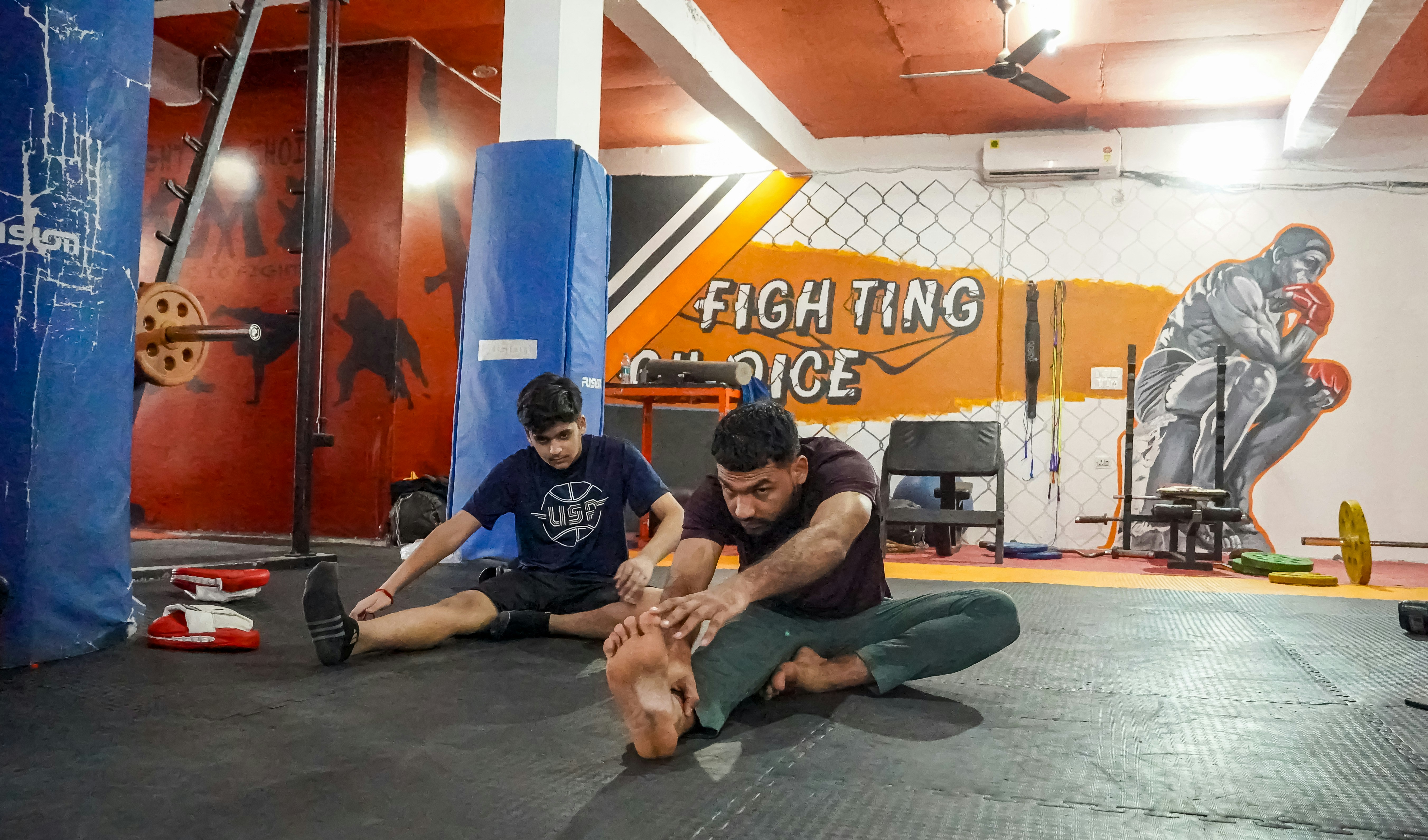 A couple of men sitting on top of a wrestling mat