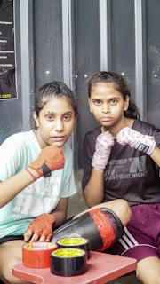 Two girls sitting on a bench with gloves on