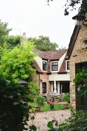 Brick and rendered cottage with a tiled roof and a garden terrace