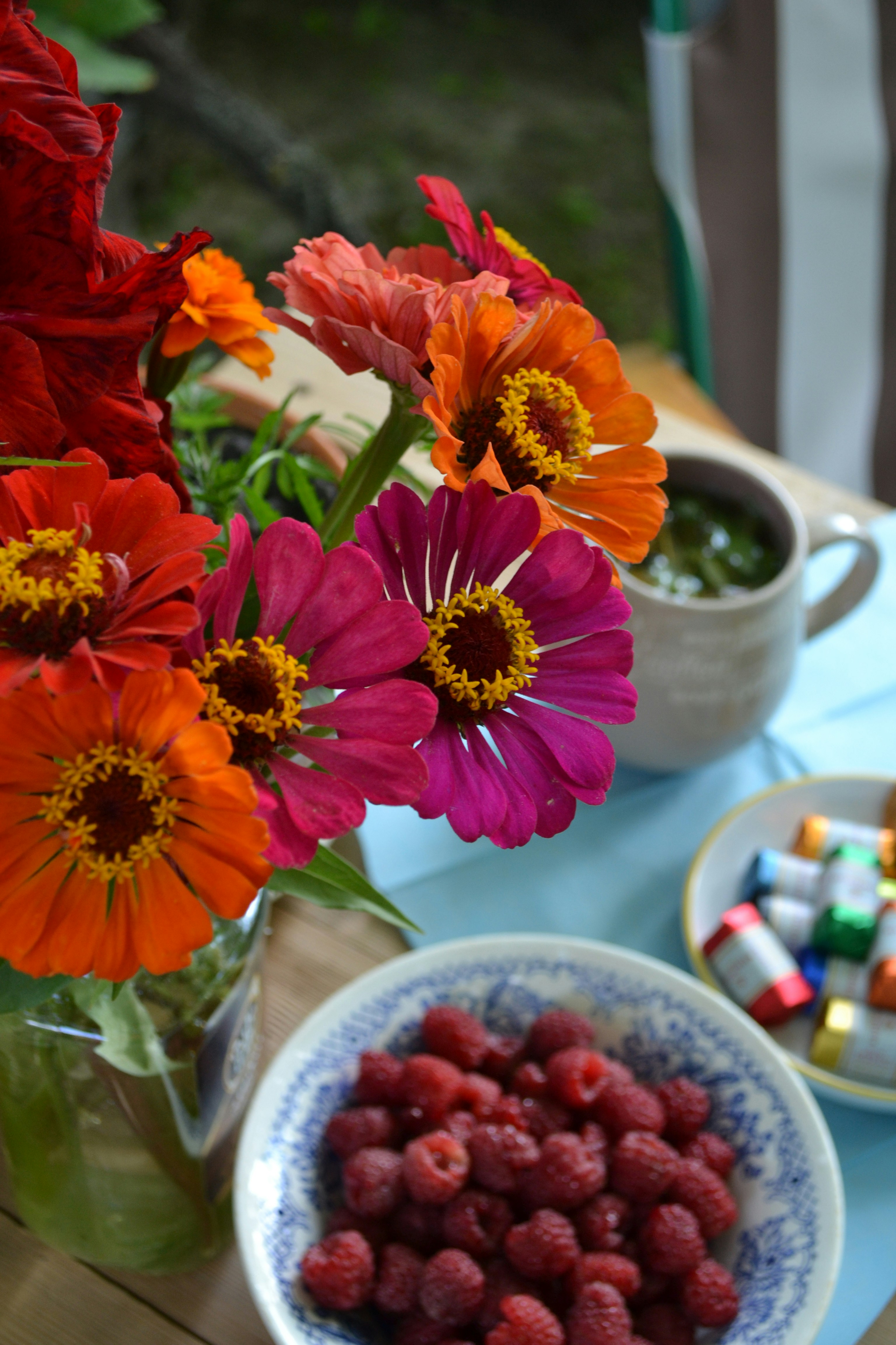 A bowl of raspberries and a bowl of flowers on a table