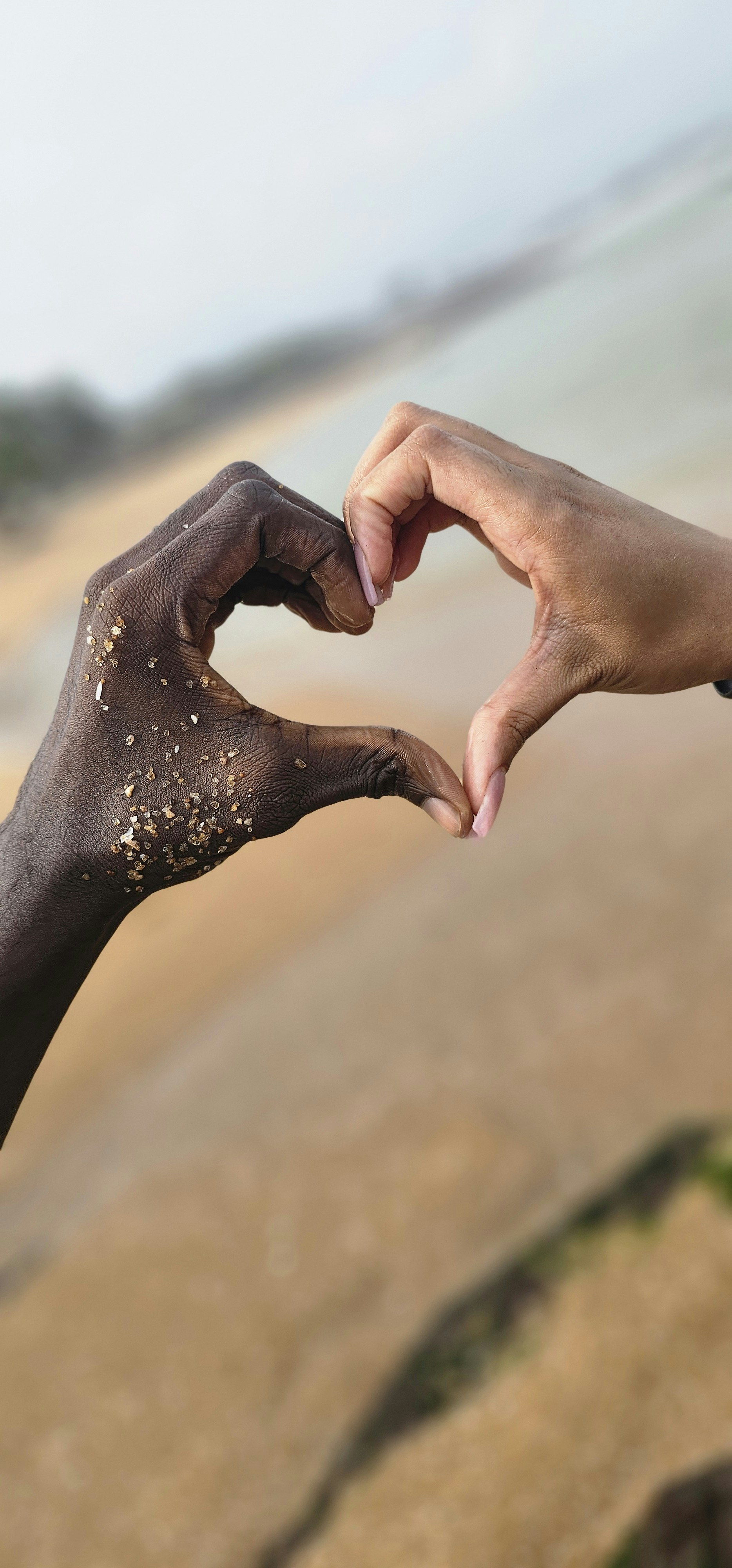 Two hands reaching out towards each other on a beach