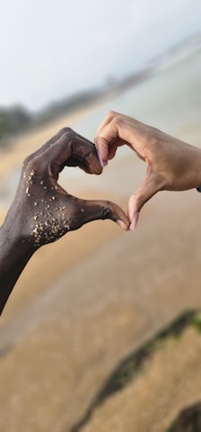 Two hands reaching out towards each other on a beach