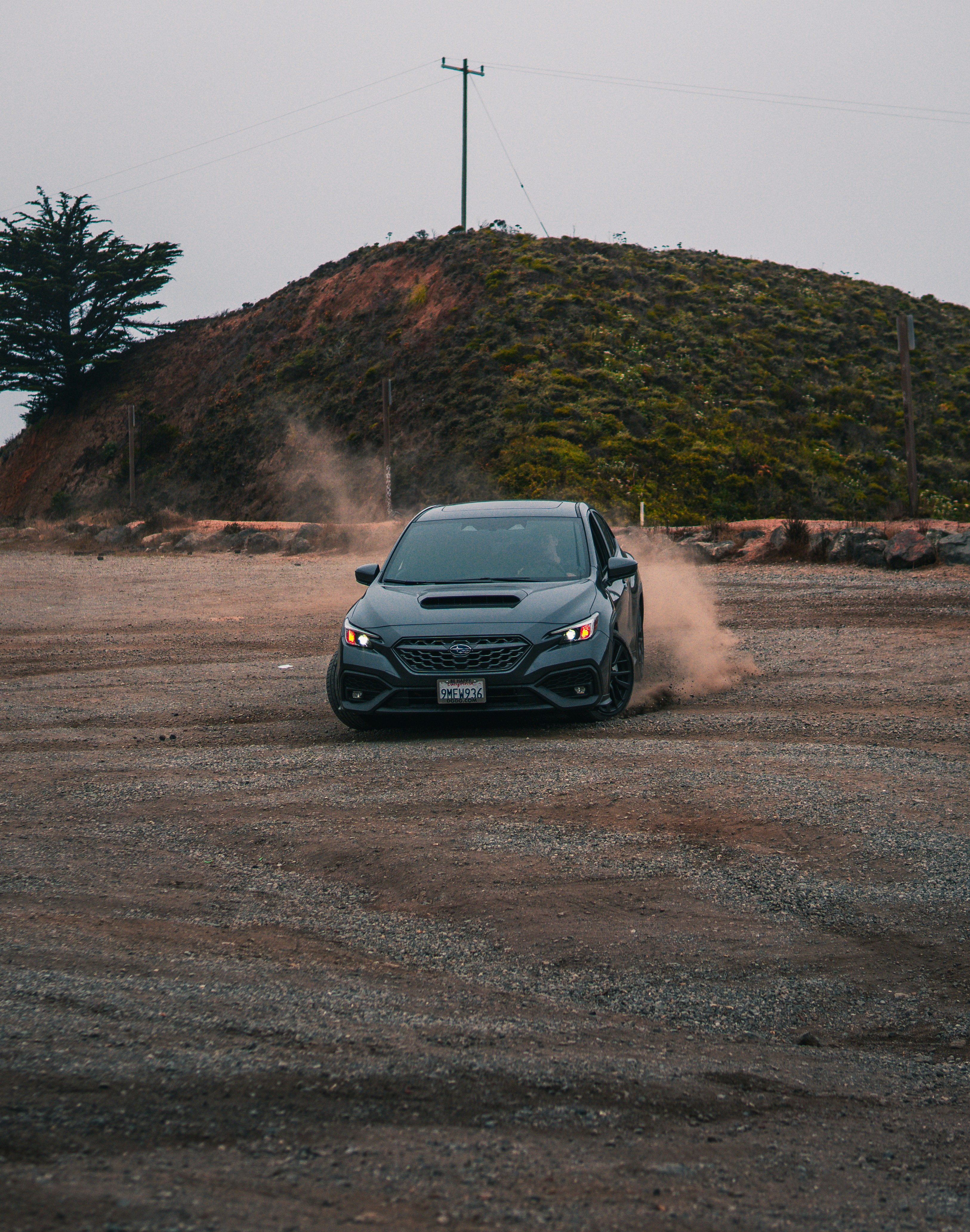 丘の近くの未舗装の道路を走行する車