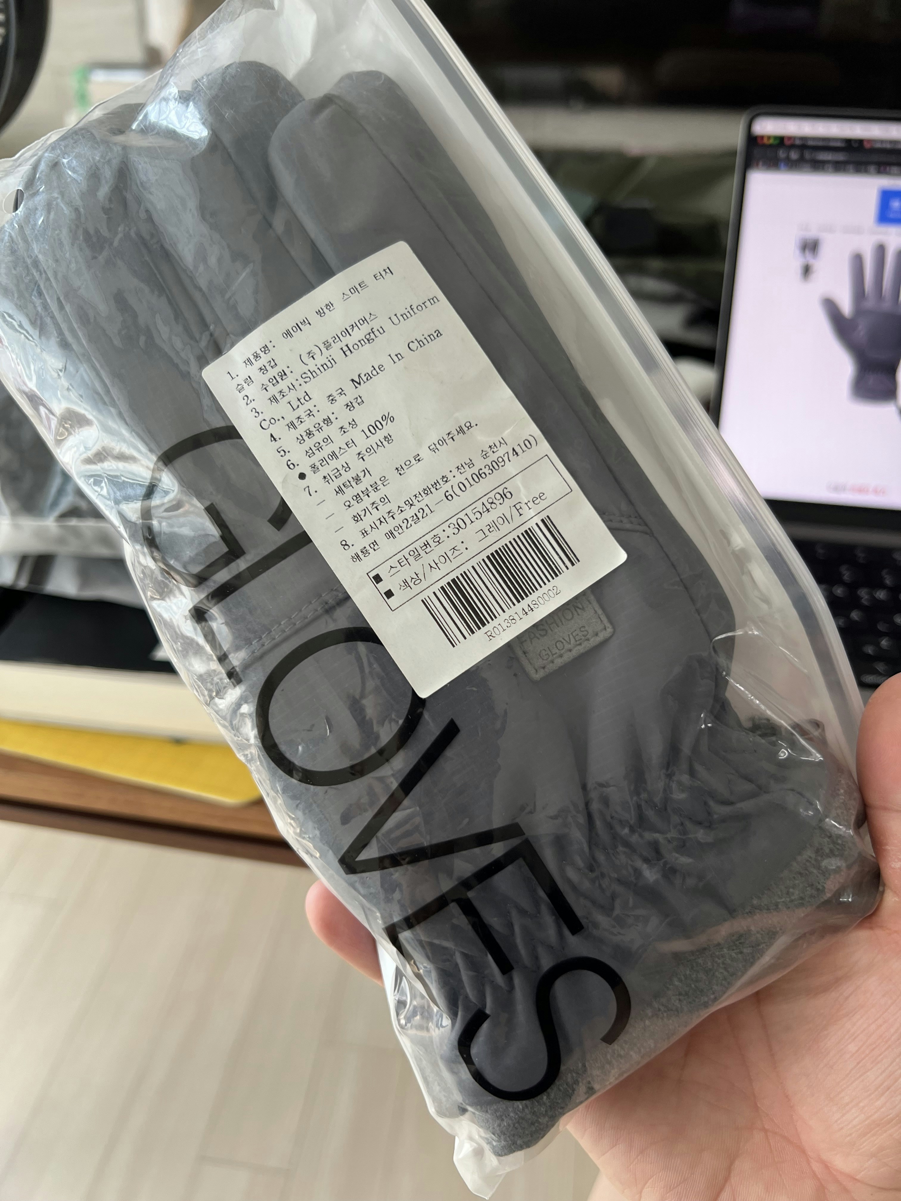A person holding a bag of gloves in front of a laptop