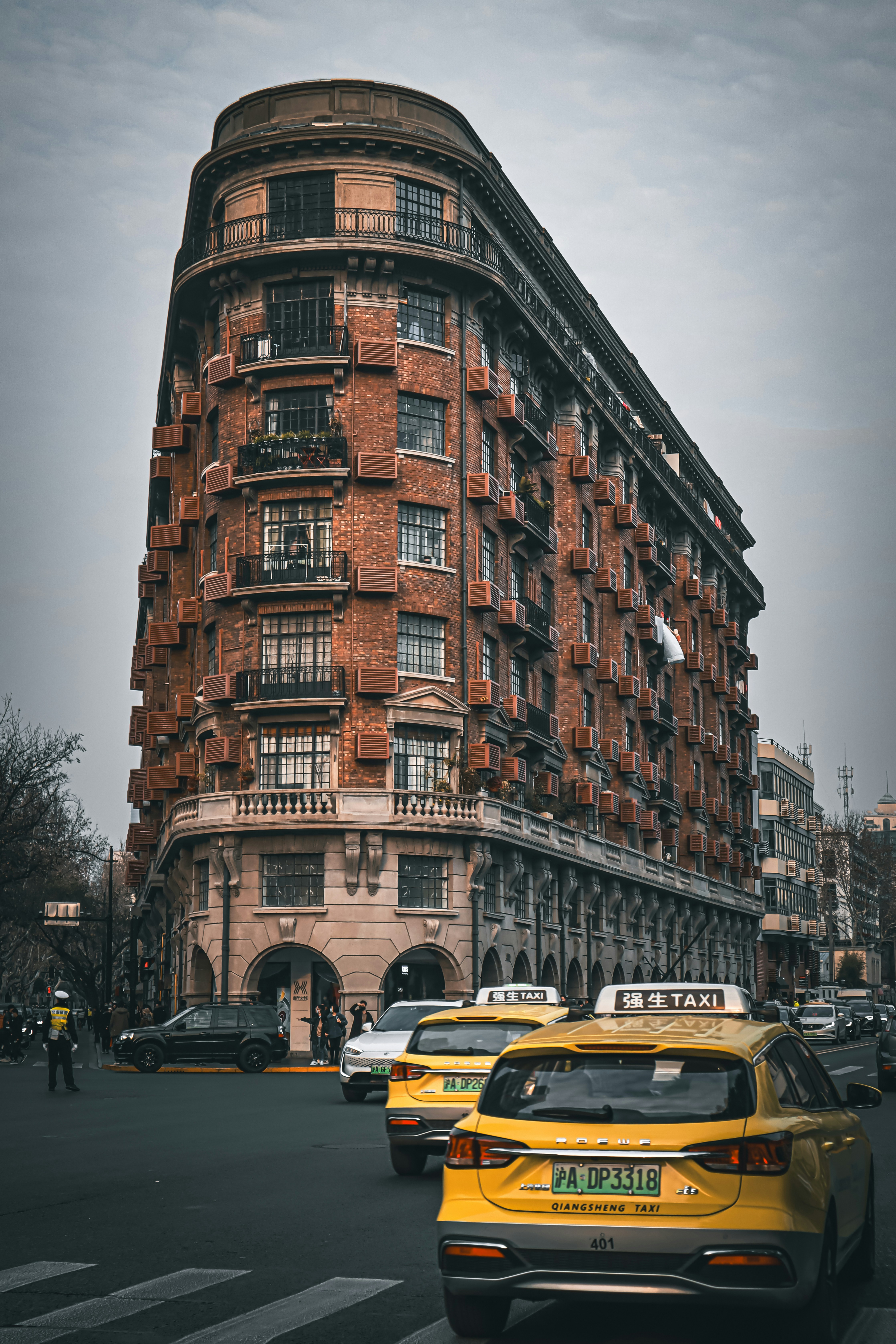 A yellow taxi cab driving down a street next to a tall building
