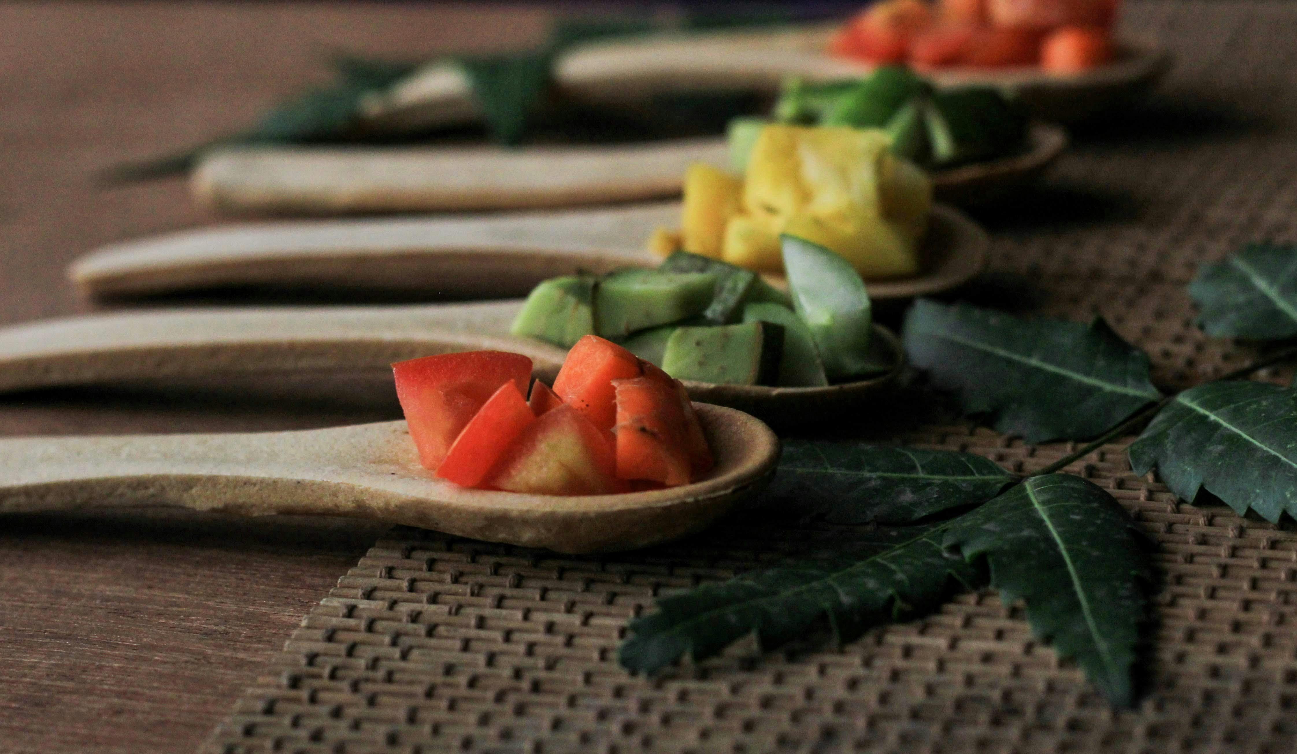 A row of wooden spoons filled with fruit