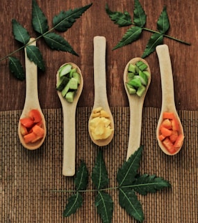 Five wooden spoons filled with different types of food