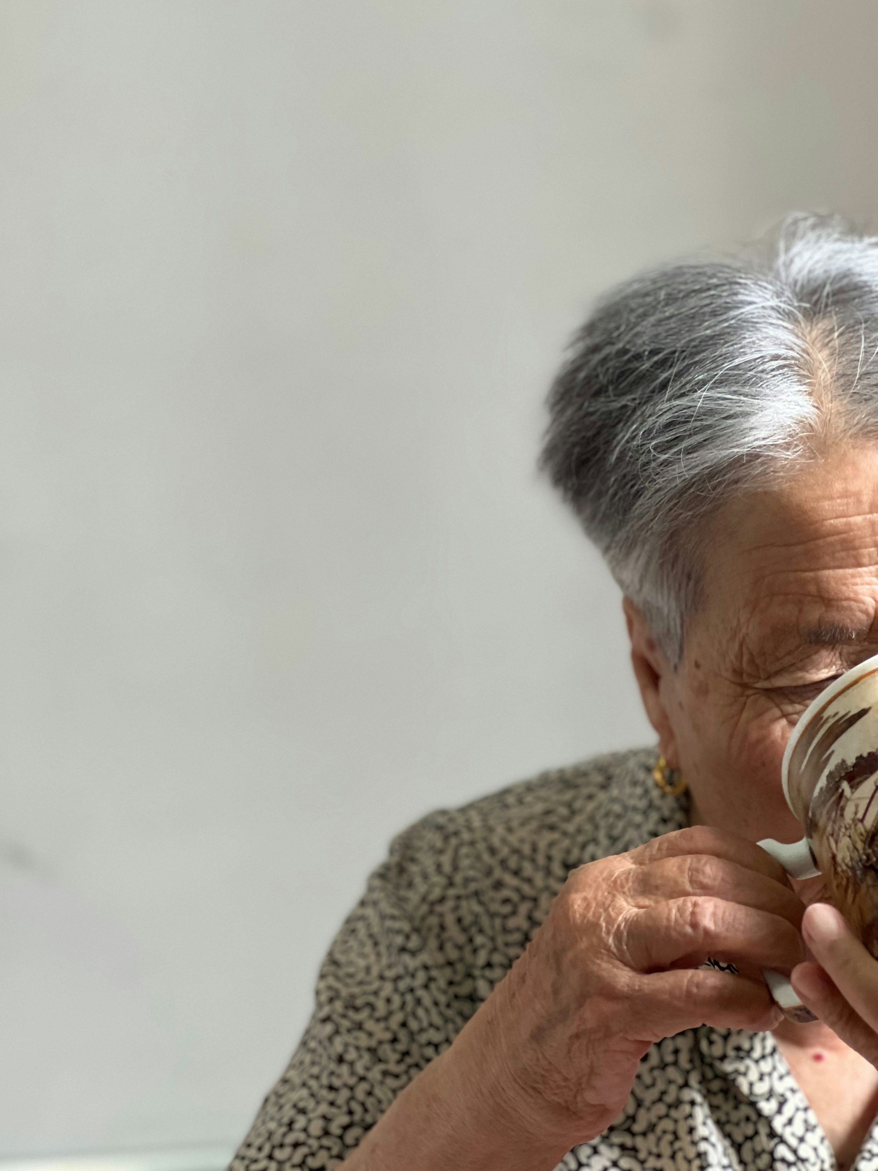 An older woman eating a donut with icing on it