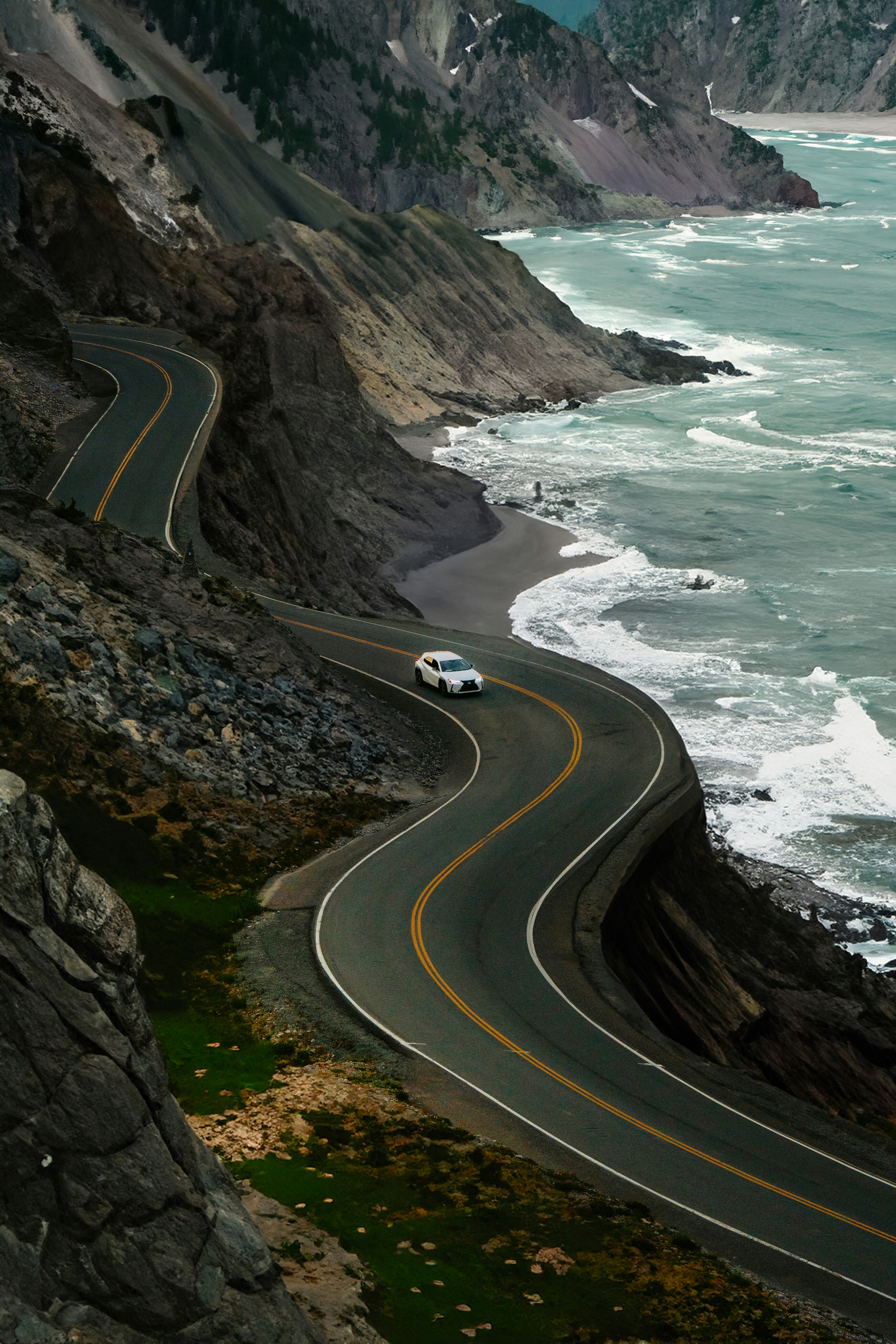 A car driving down a road next to the ocean