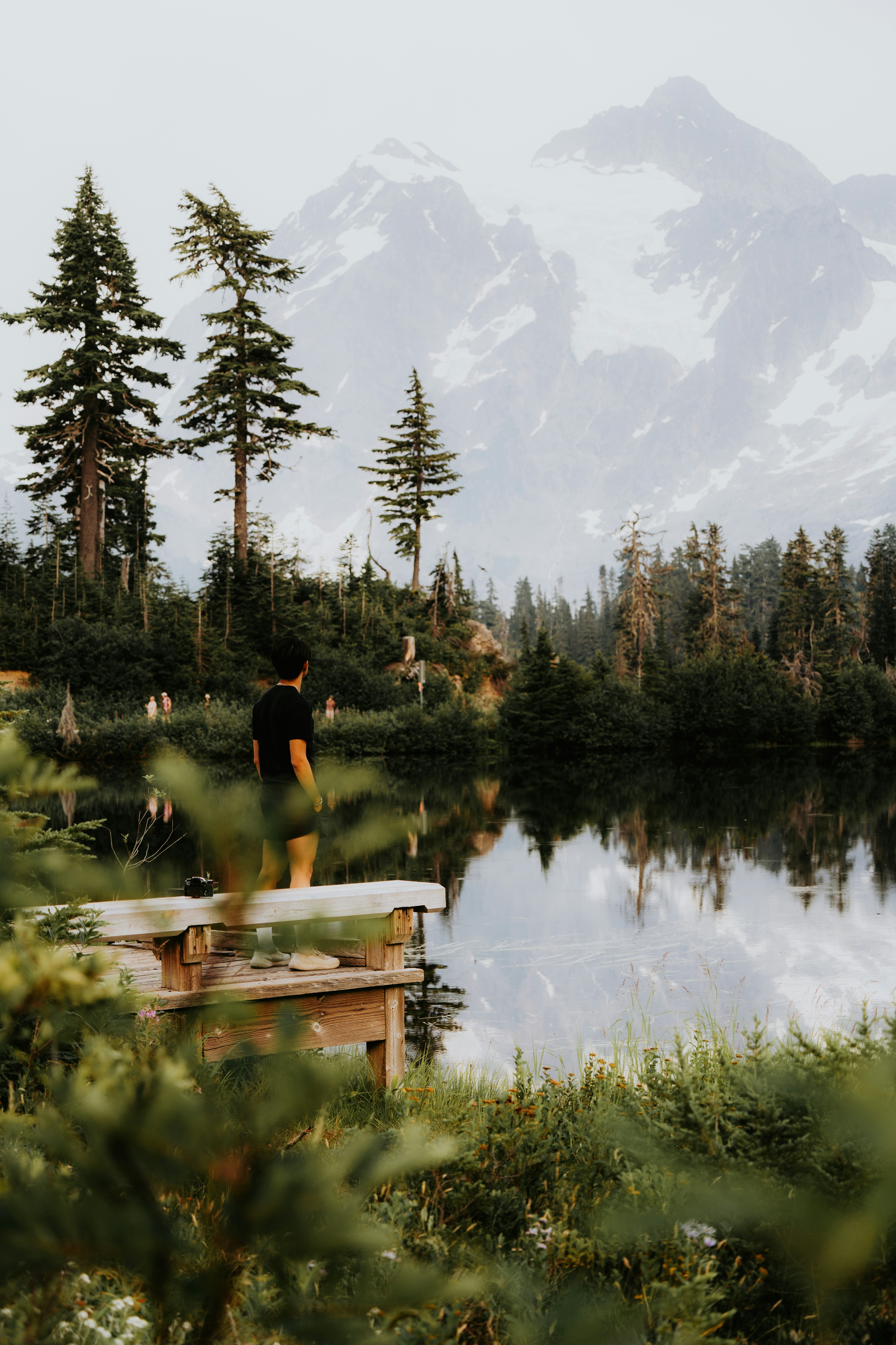 A man standing on a dock in front of a lake