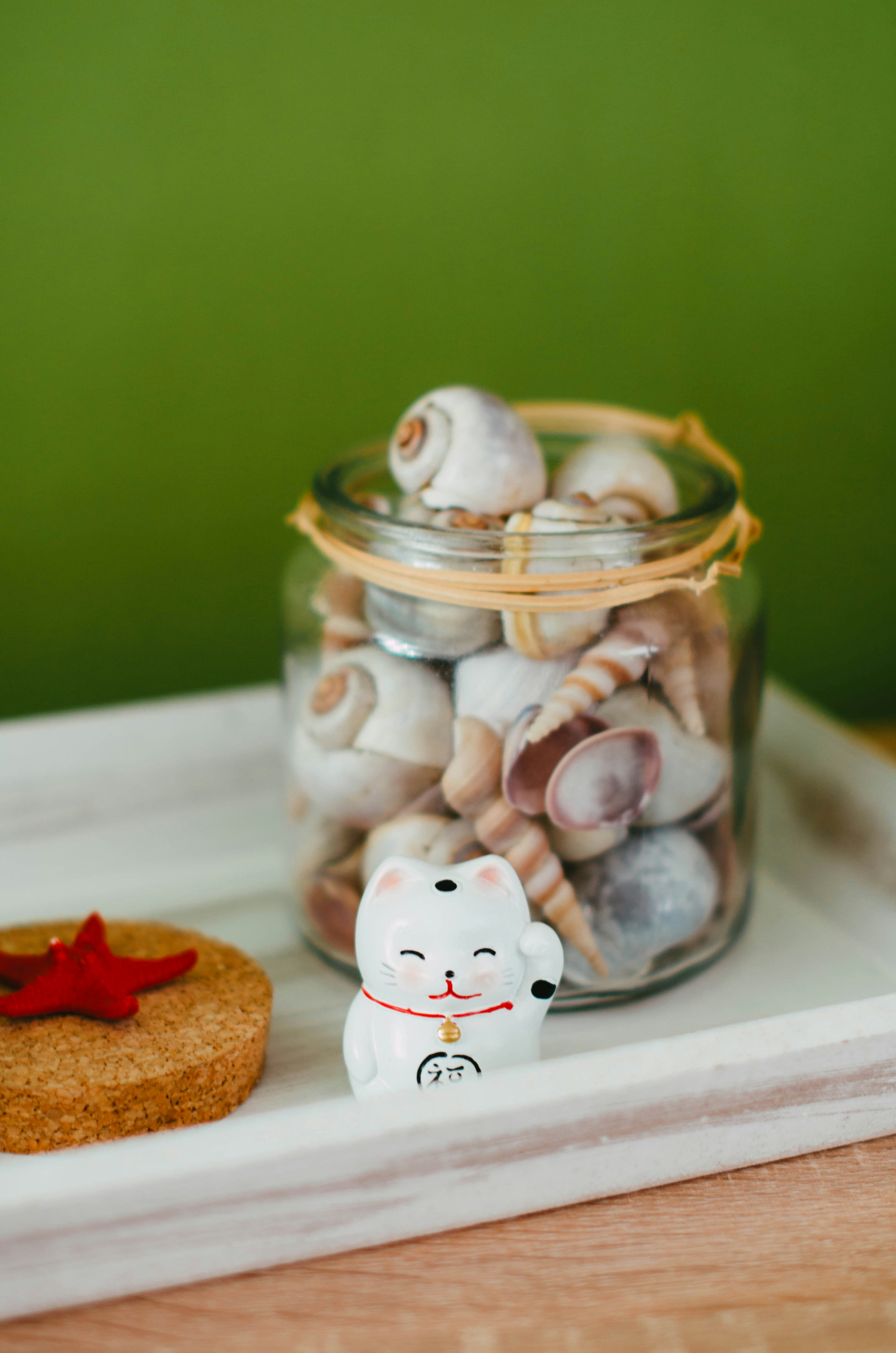 A glass jar filled with sea shells next to a cookie