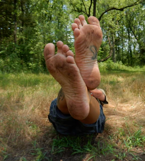 A person laying in the grass with their feet up