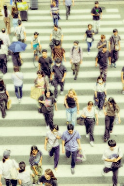 A crowd of people walking across a cross walk
