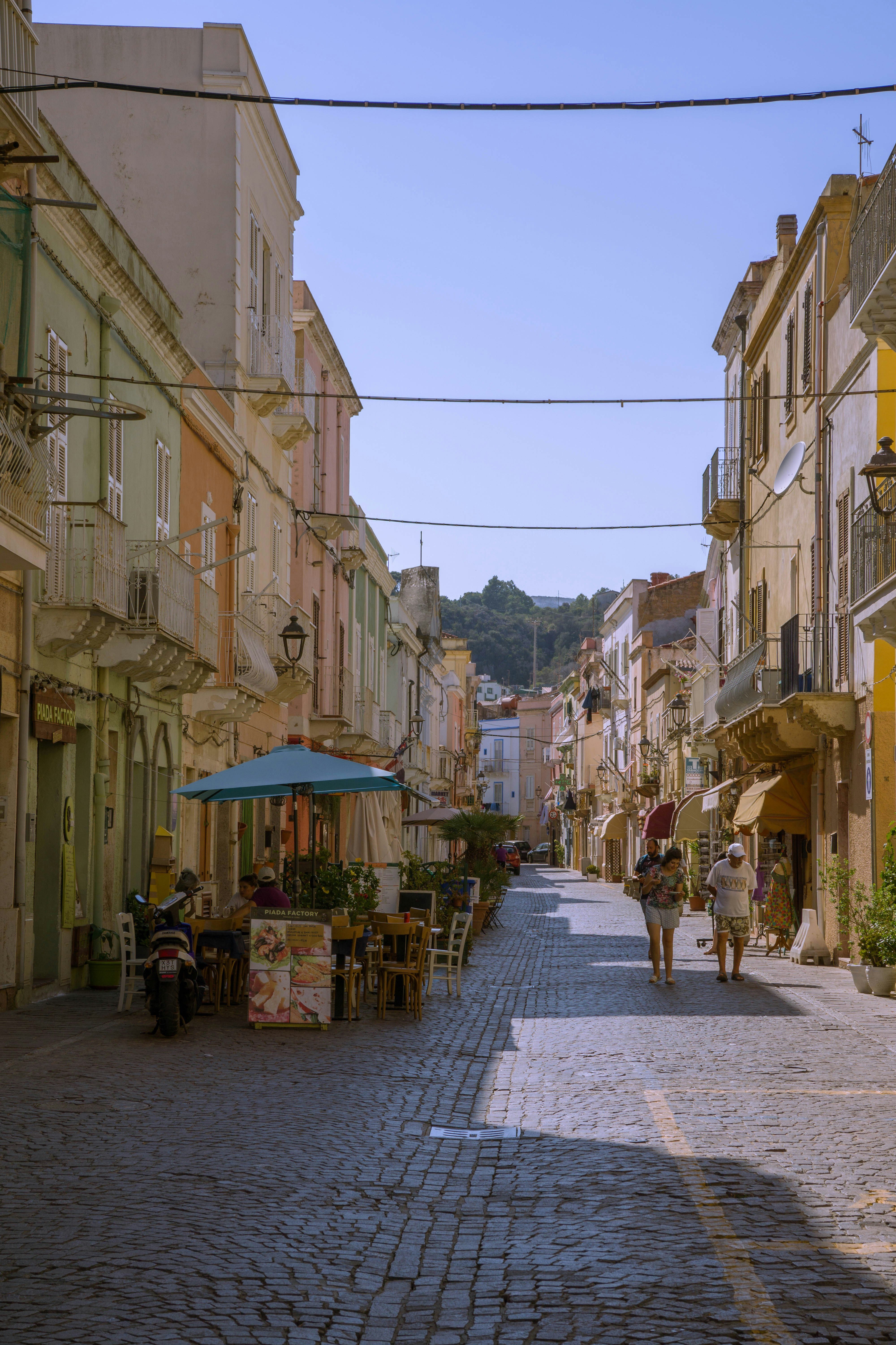 A cobblestone street with people walking down it
