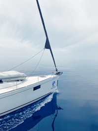 A white sailboat floating on top of a body of water