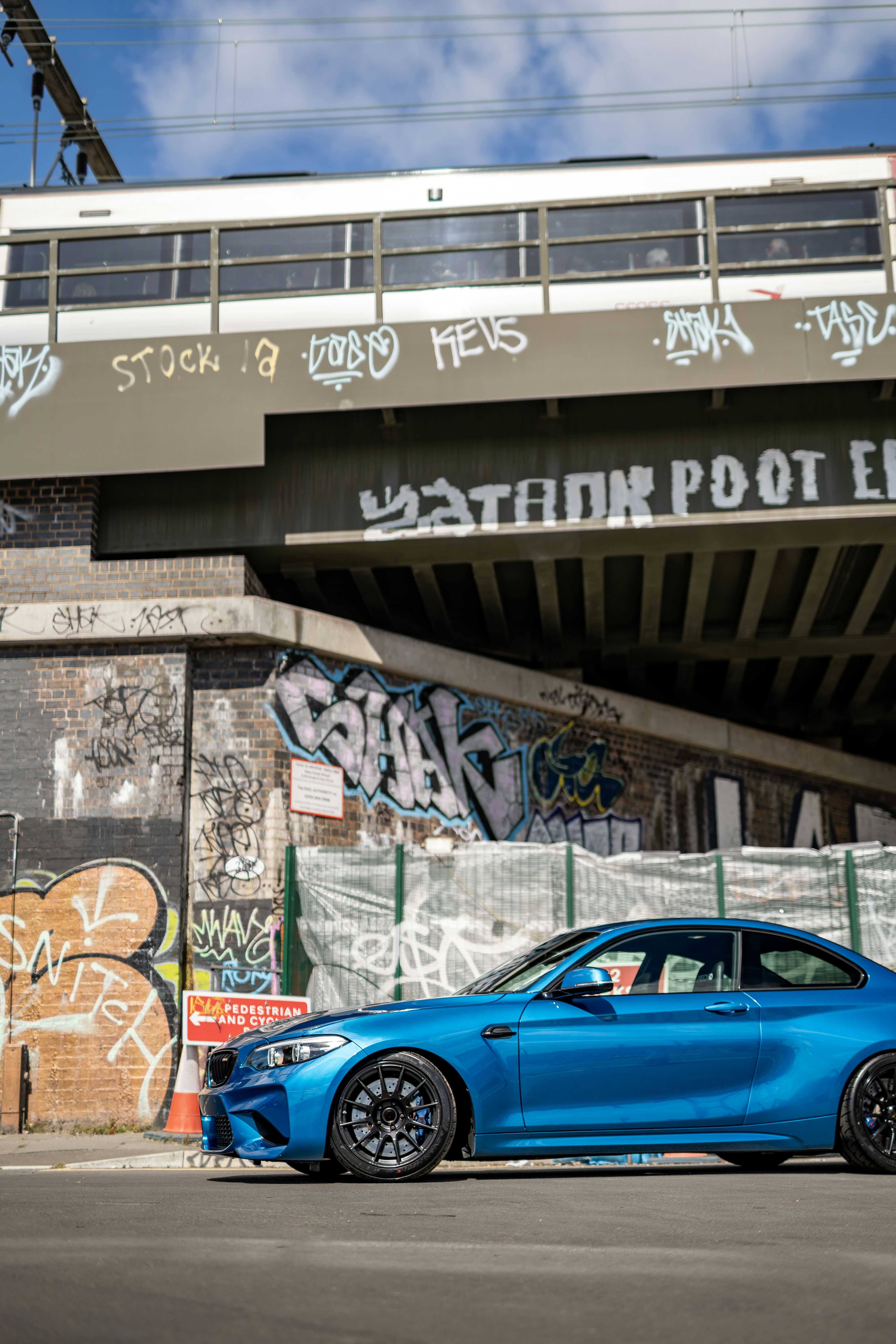 A blue car parked in front of a bridge