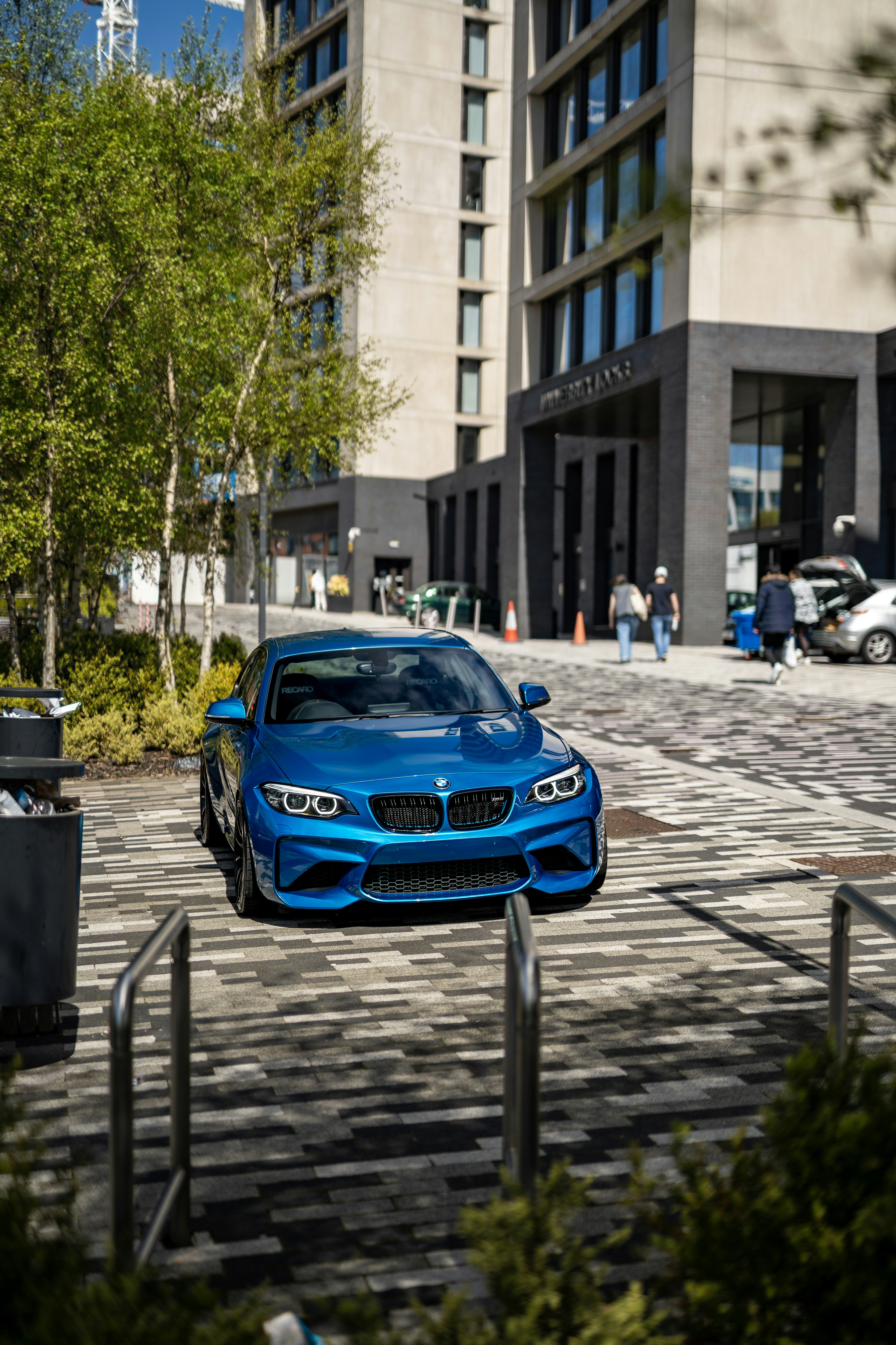 A blue car parked in front of a tall building