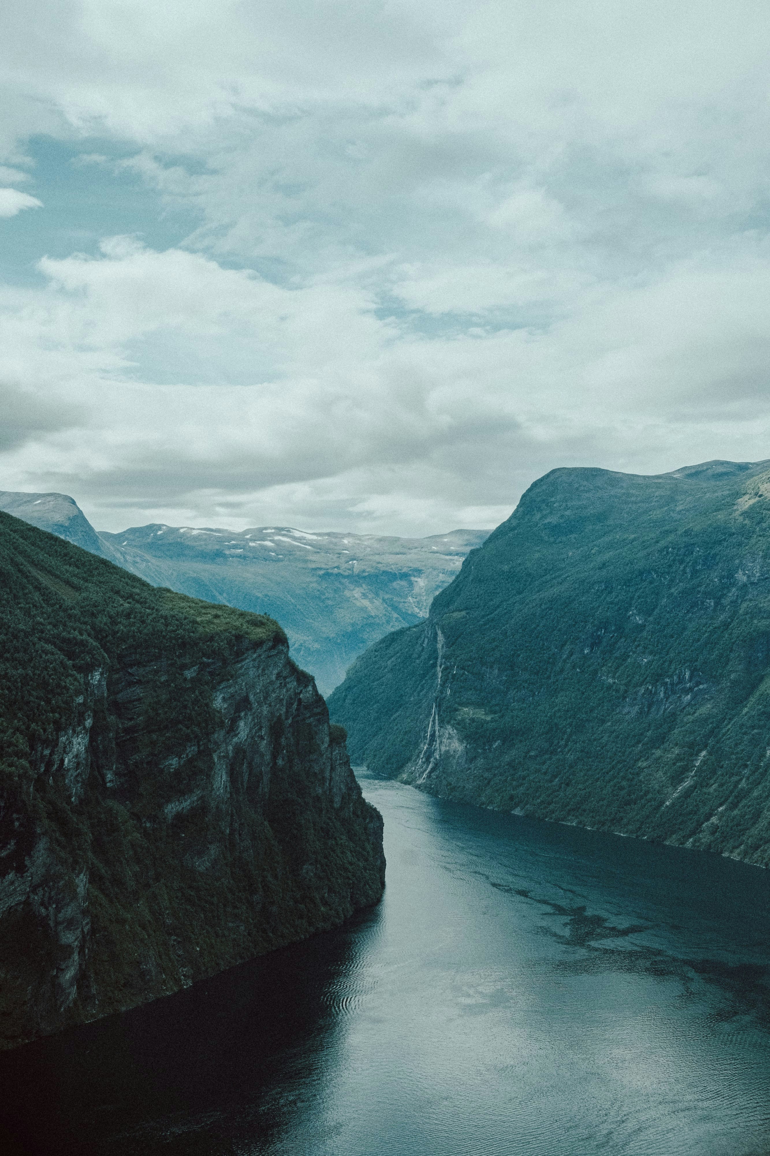 A body of water surrounded by mountains under a cloudy sky