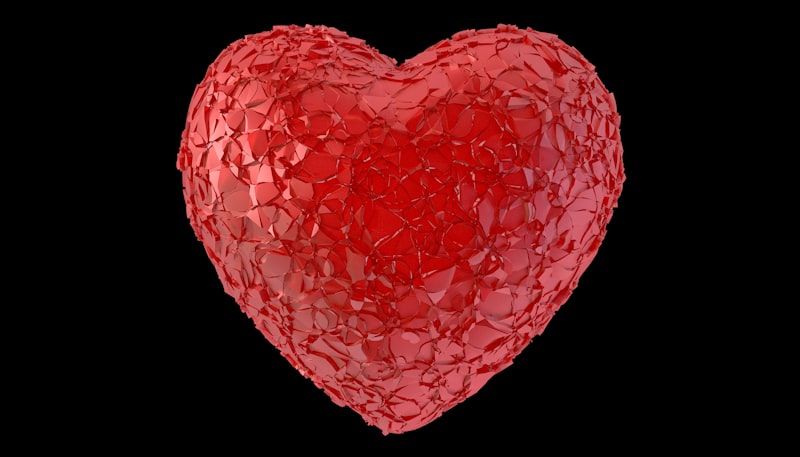 A red heart shaped object with a black background