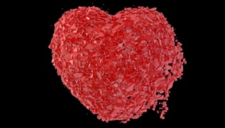 A red heart shaped object with a black background