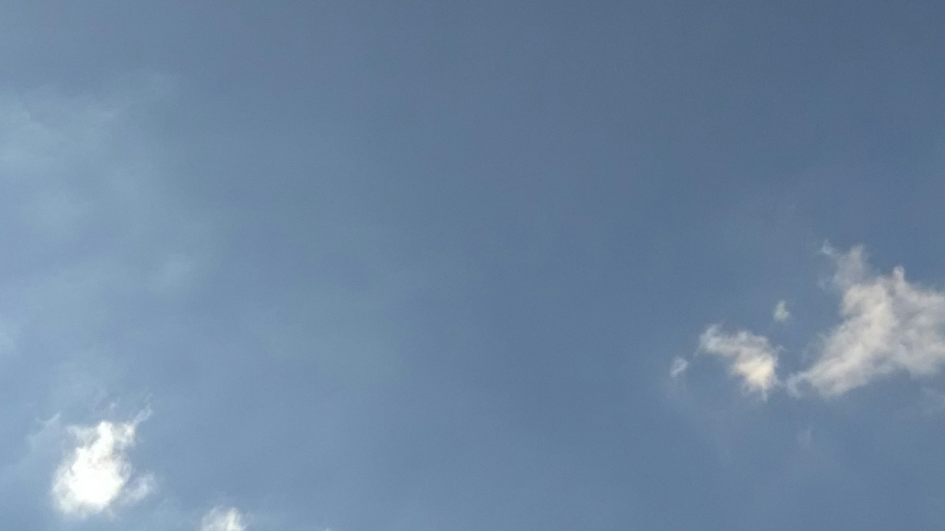 A plane flying through a blue sky with clouds