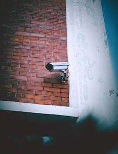 A security camera mounted to the side of a brick building