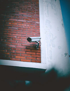 A security camera mounted to the side of a brick building