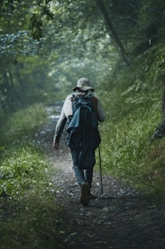 A man with a backpack walks down a path in the woods
