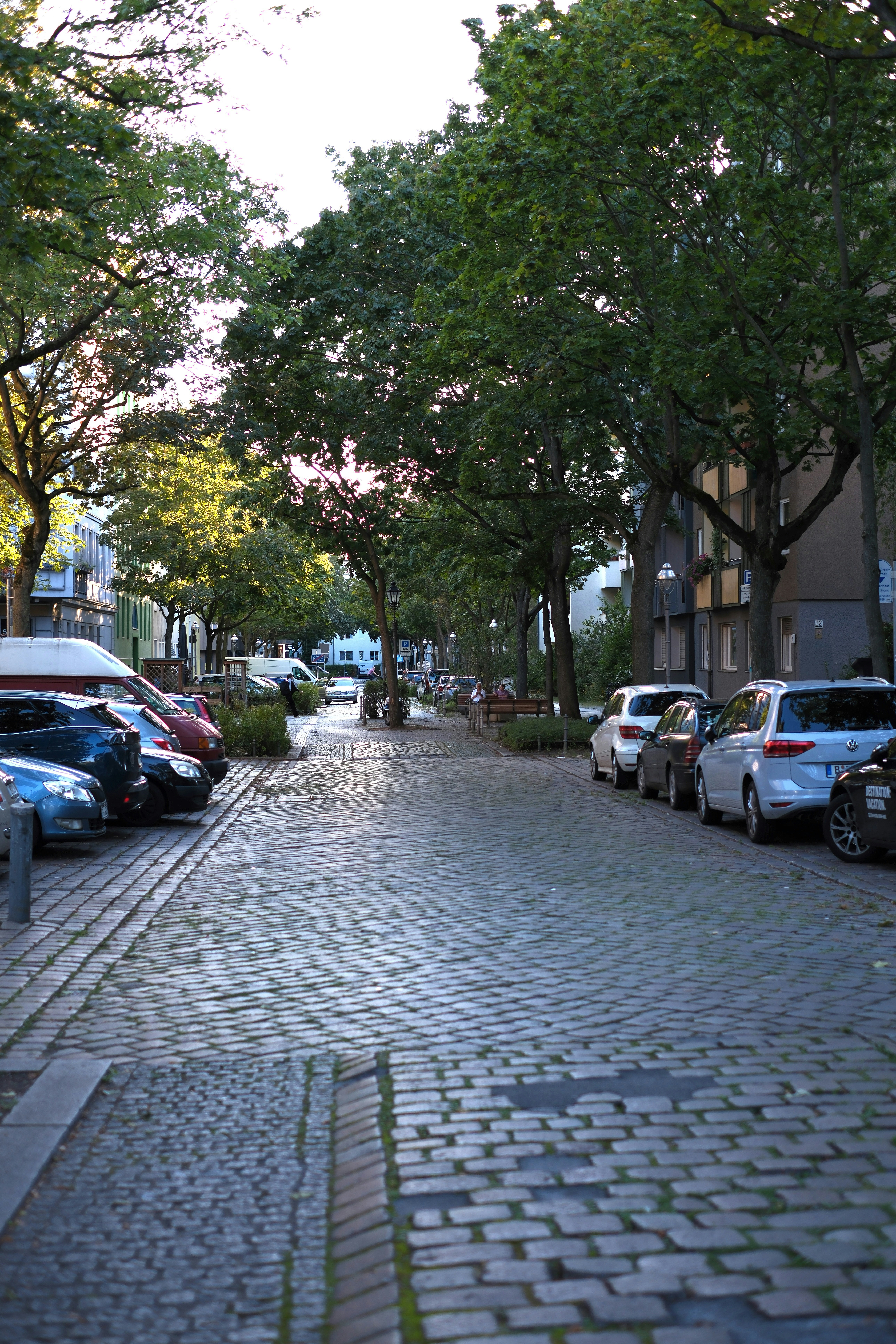 A cobblestone street lined with parked cars - a-cobblestone-street-lined-with-parked-cars-aAI9lg1Qb2k