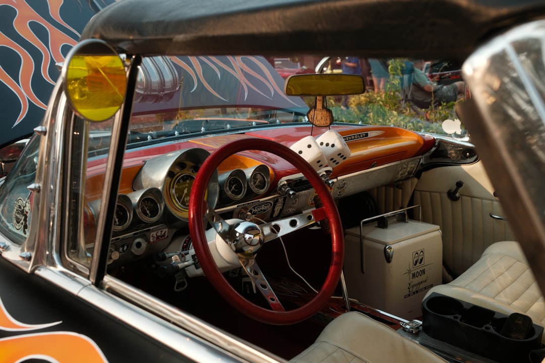 The interior of a classic car with a red steering wheel,