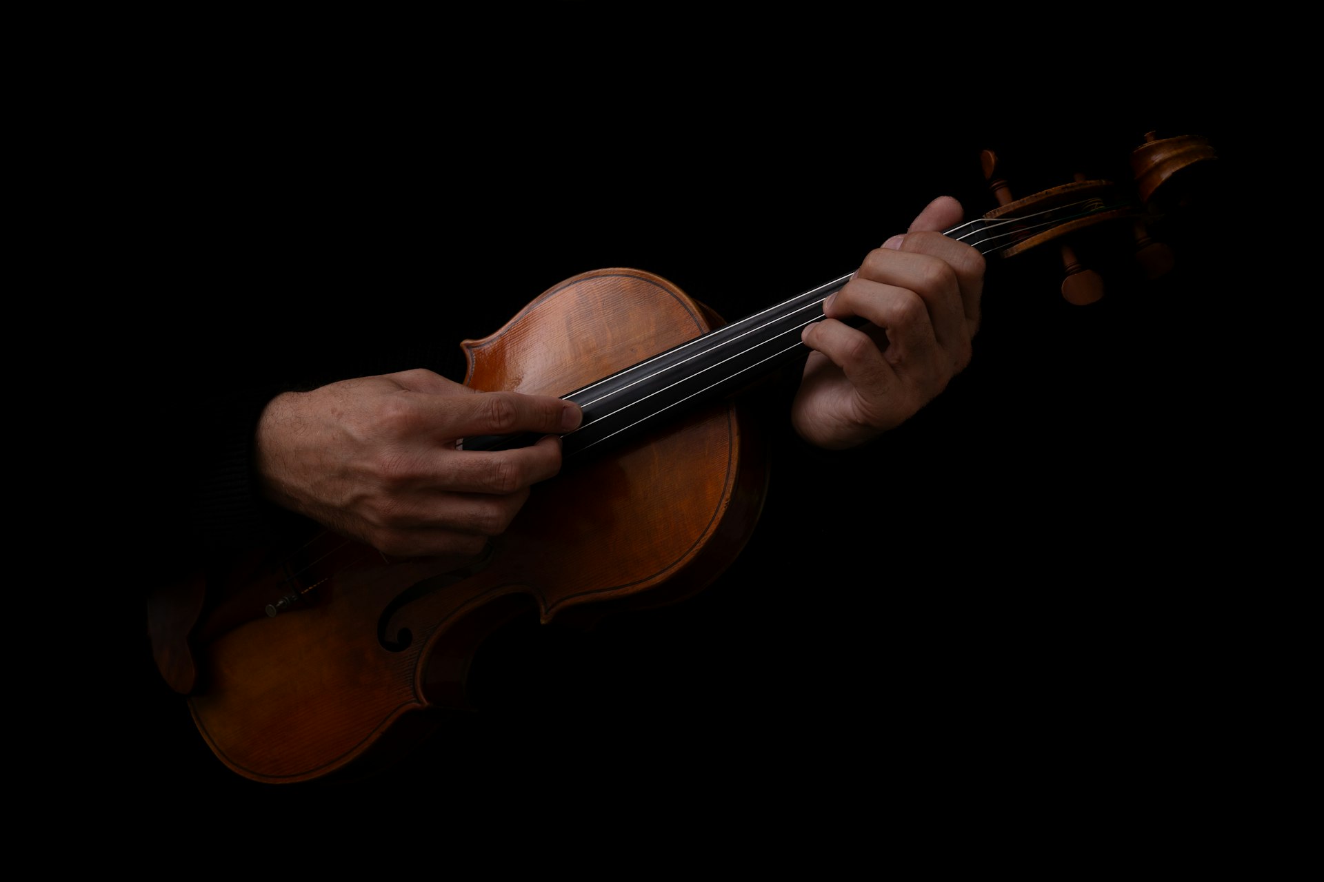 Man playing violin in the dark, dramatic lighting