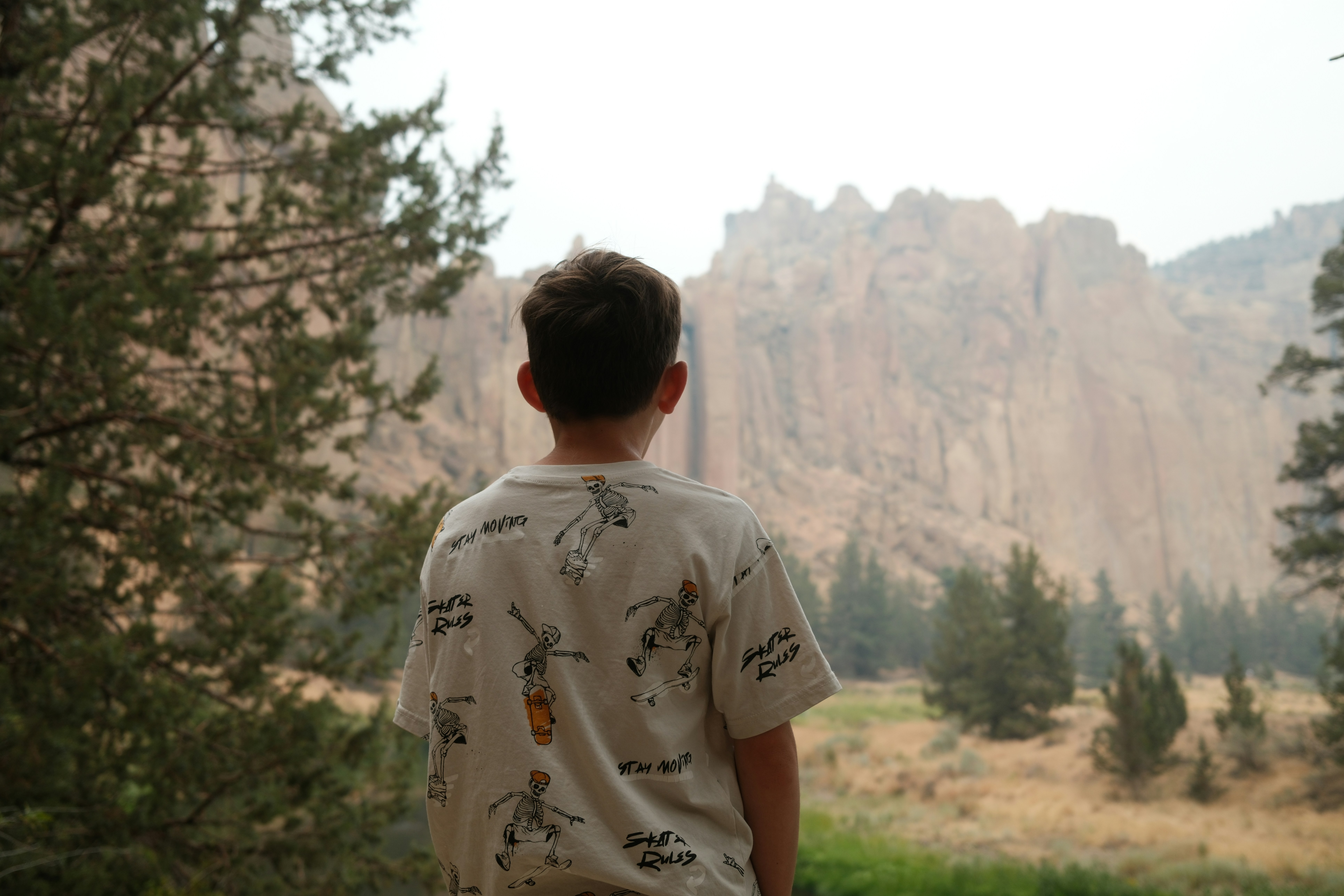 A young boy standing in front of a mountain