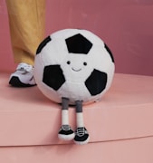 A stuffed soccer ball sitting on top of a pink surface