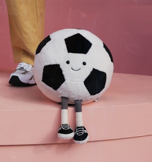 A stuffed soccer ball sitting on top of a pink surface