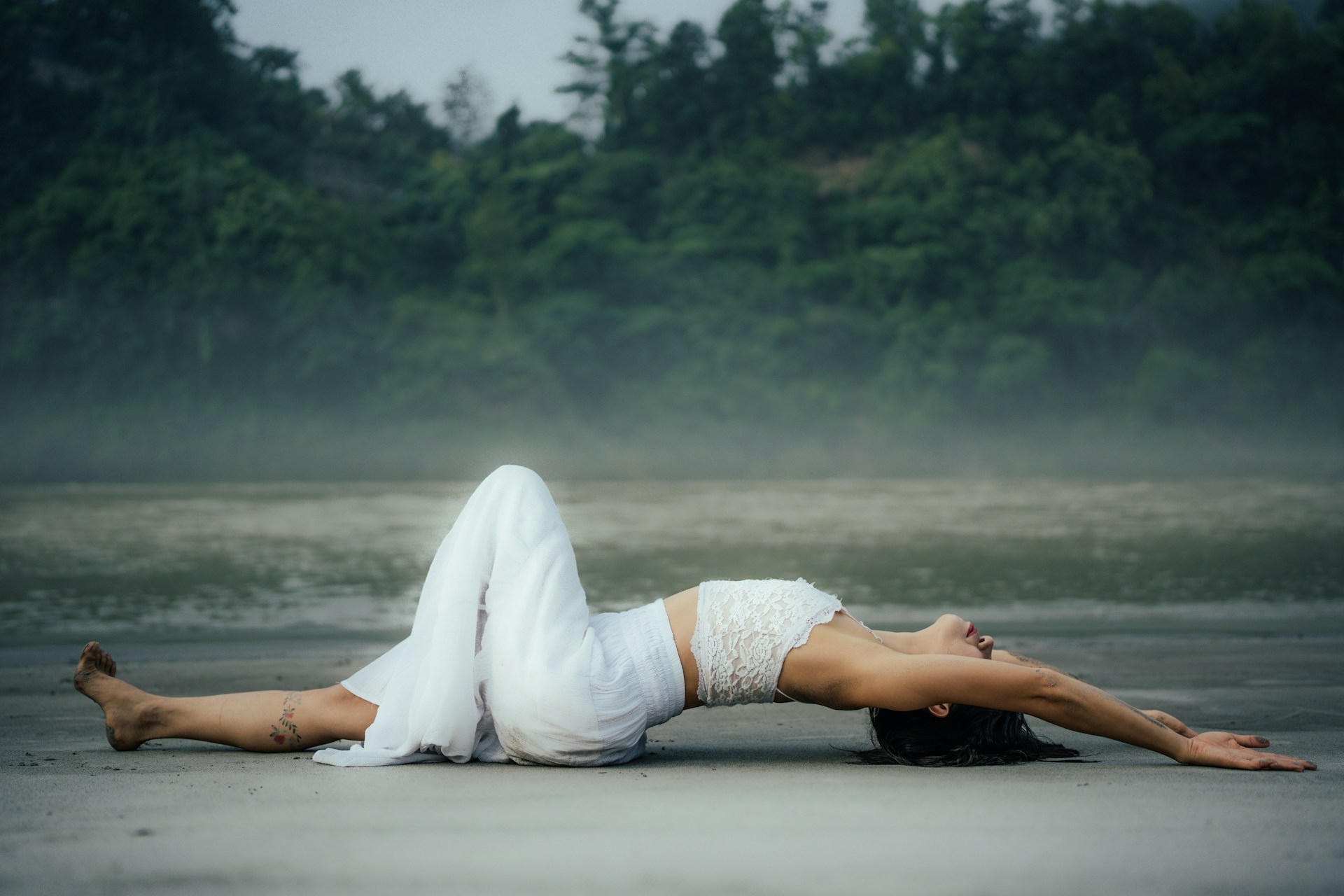 A woman laying on her back on the beach