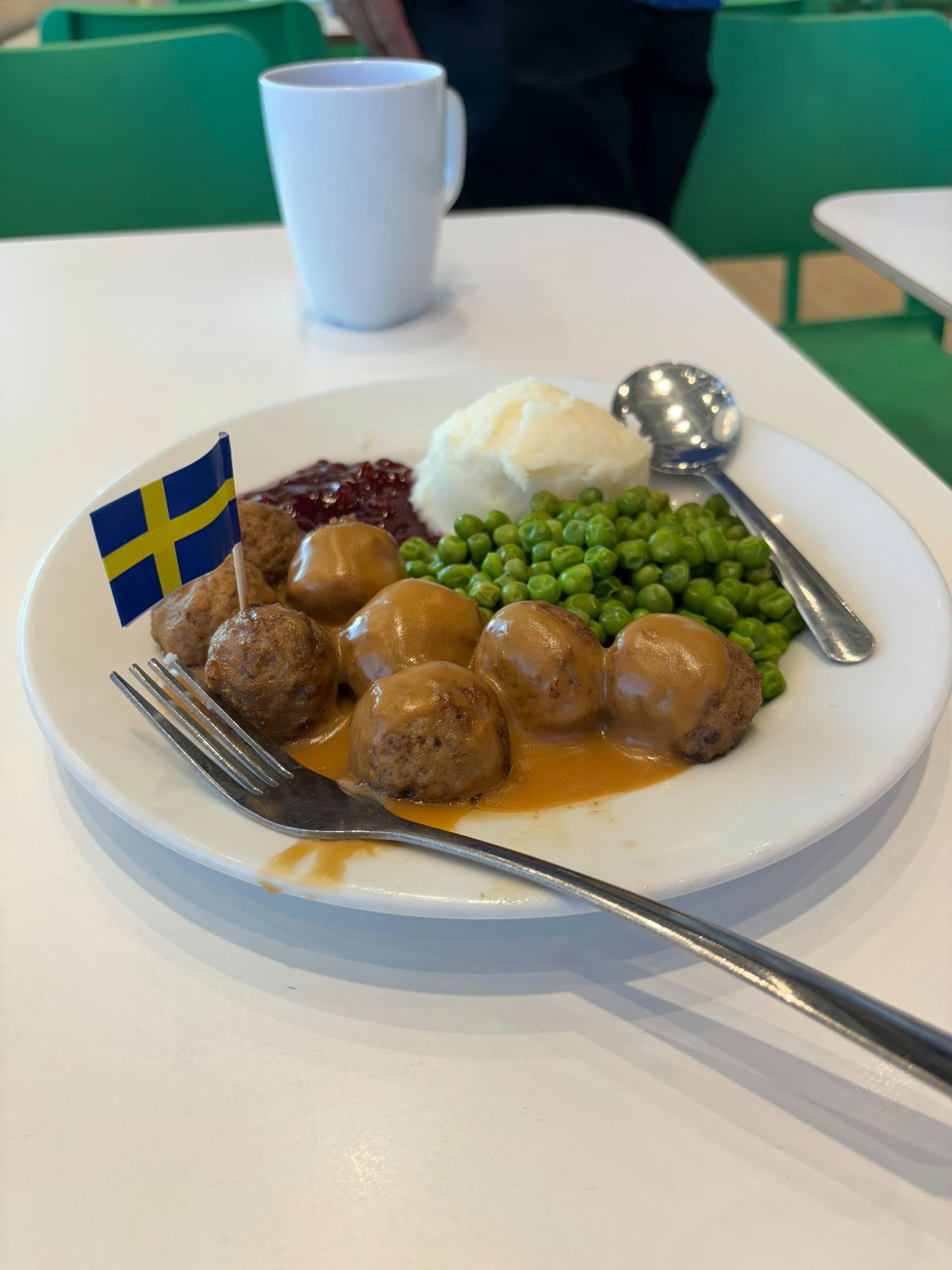 A plate of food with meatballs, mashed potatoes, peas, and a