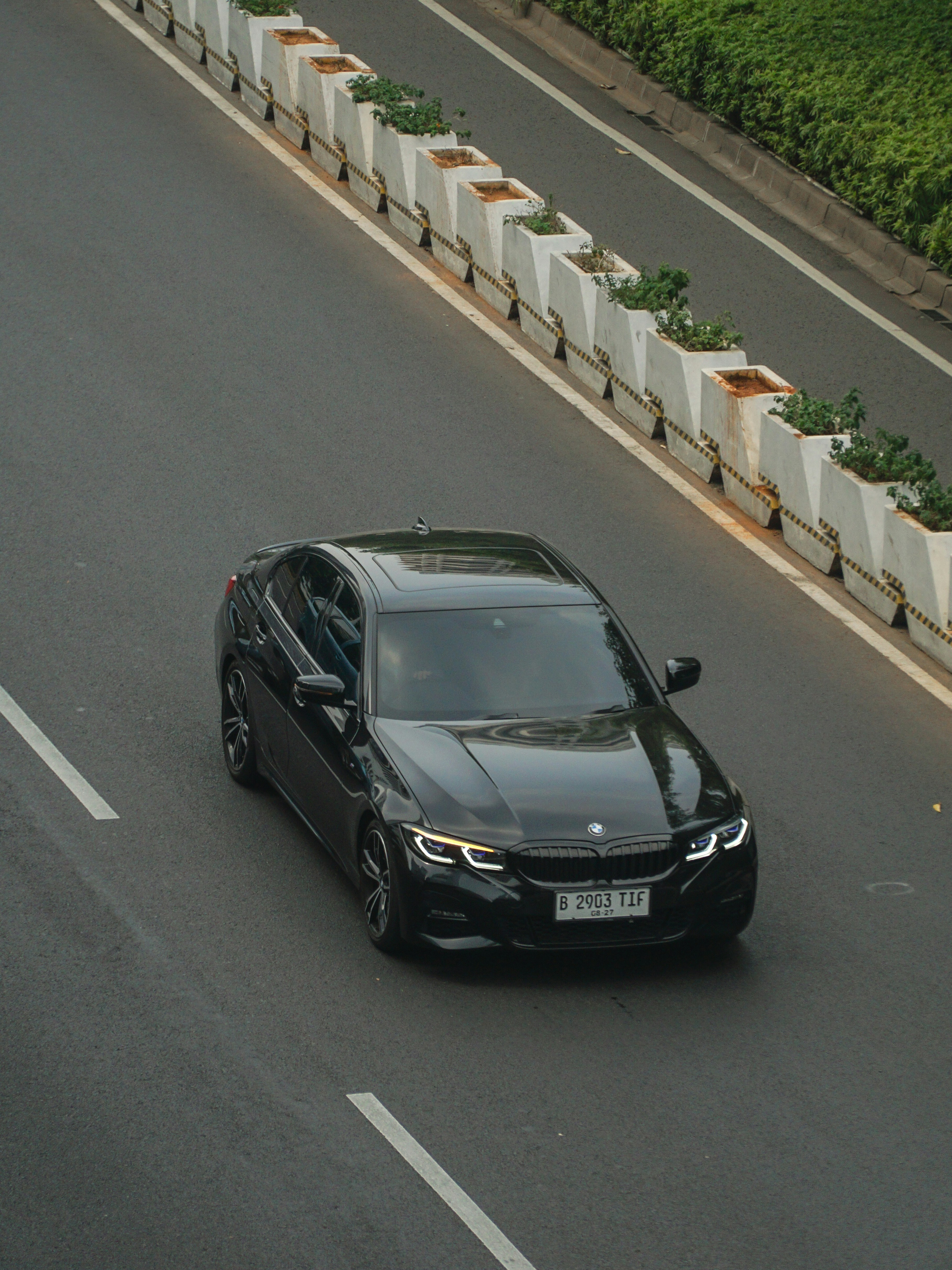 A black car driving down a street next to a fence