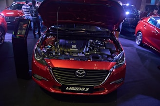 A red car with its hood open in a garage