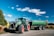 A large green truck driving down a rural road
