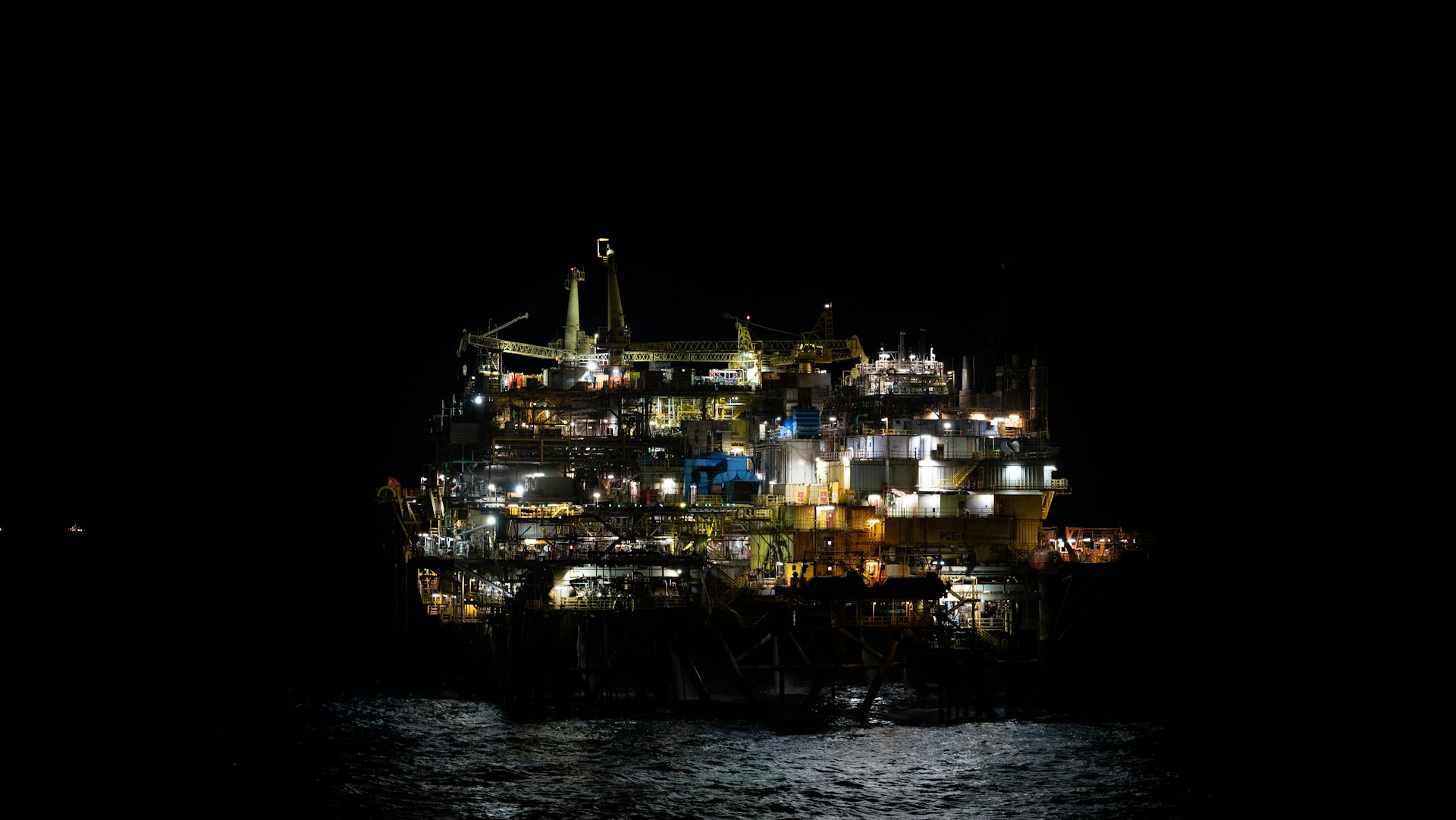 An oil rig in the middle of the ocean at night
