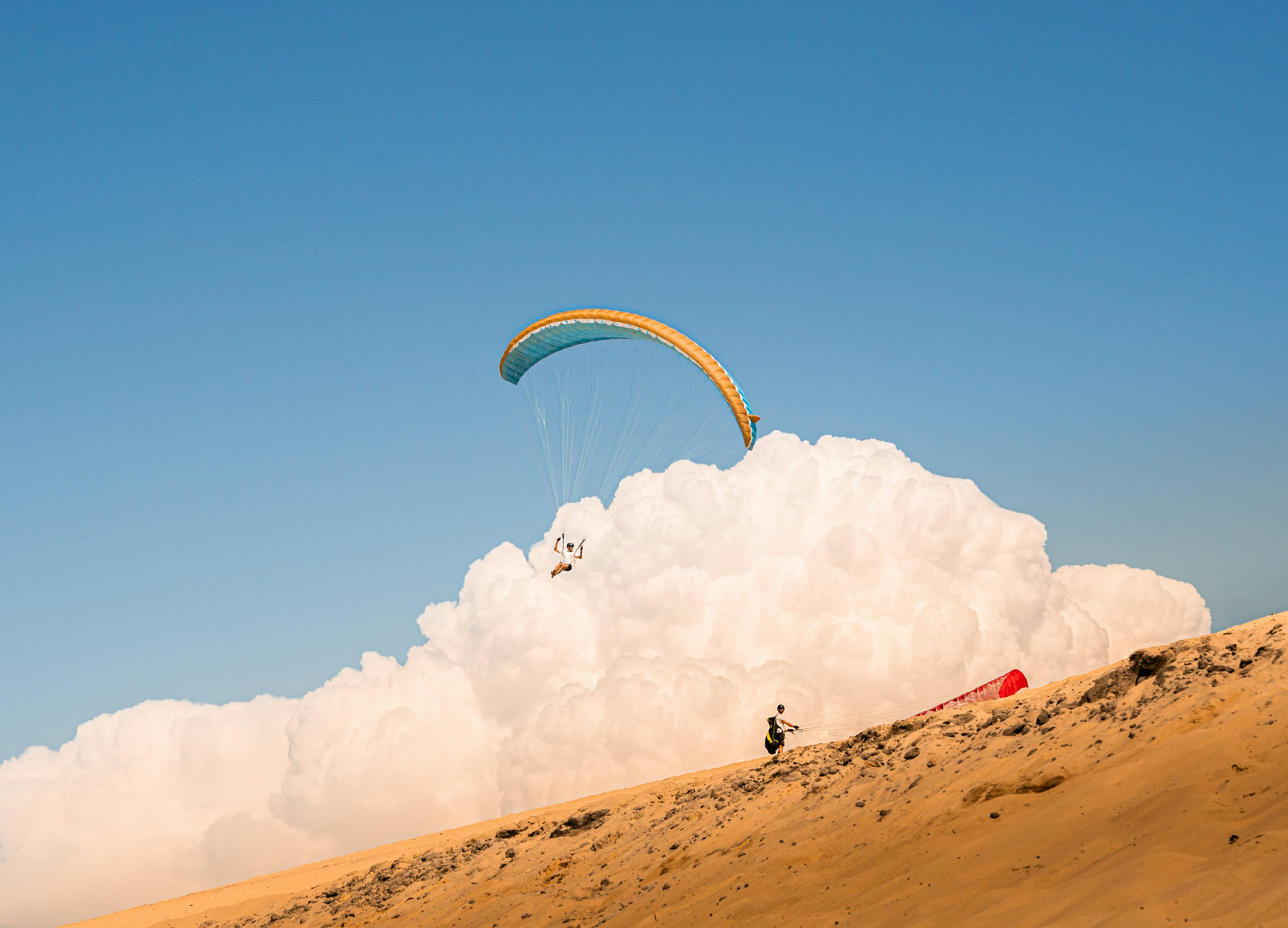 A person riding a kite board on top of a sandy hill