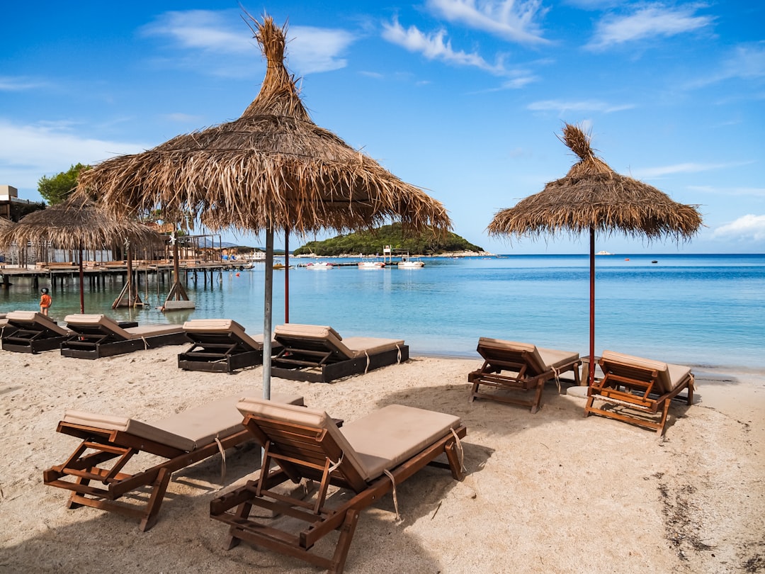 Una spiaggia sabbiosa con sedie a sdraio e ombrelloni di paglia