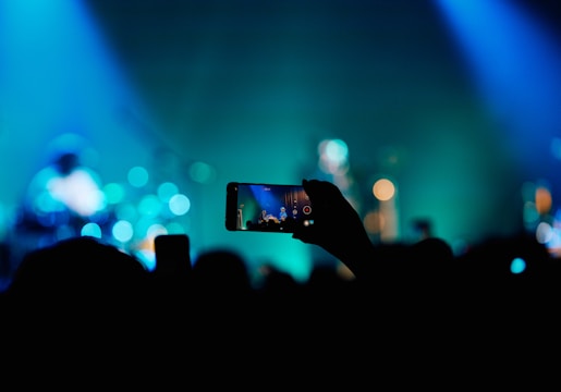 A person taking a picture of a concert with a cell phone