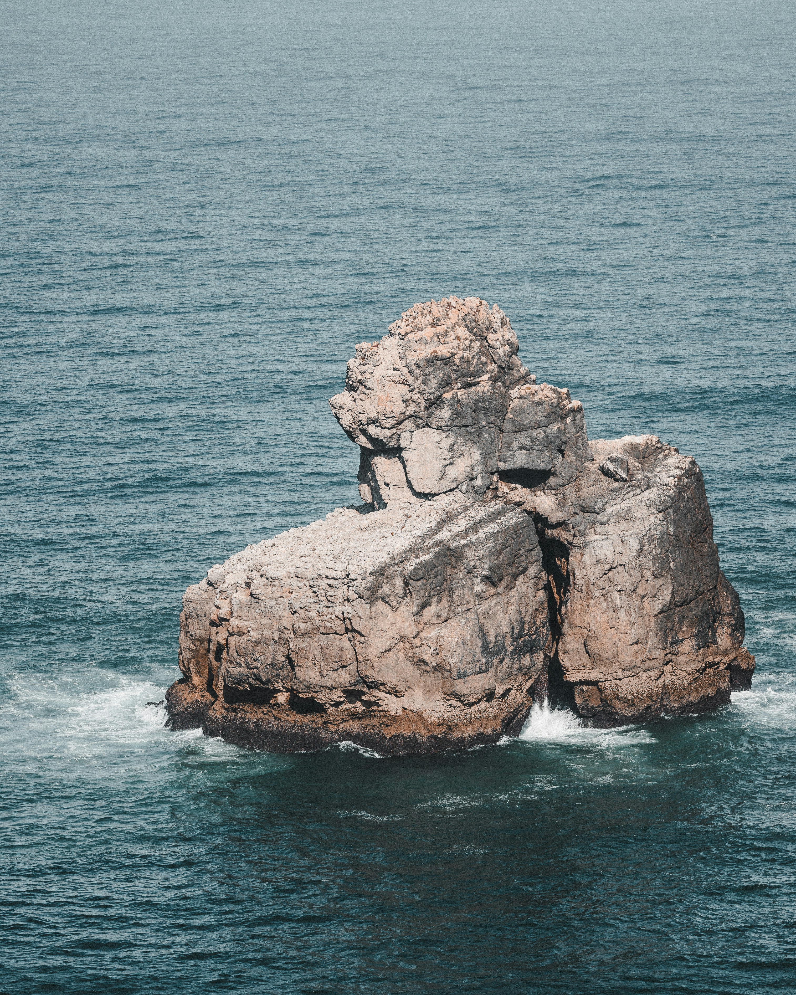 A large rock in the middle of a body of water