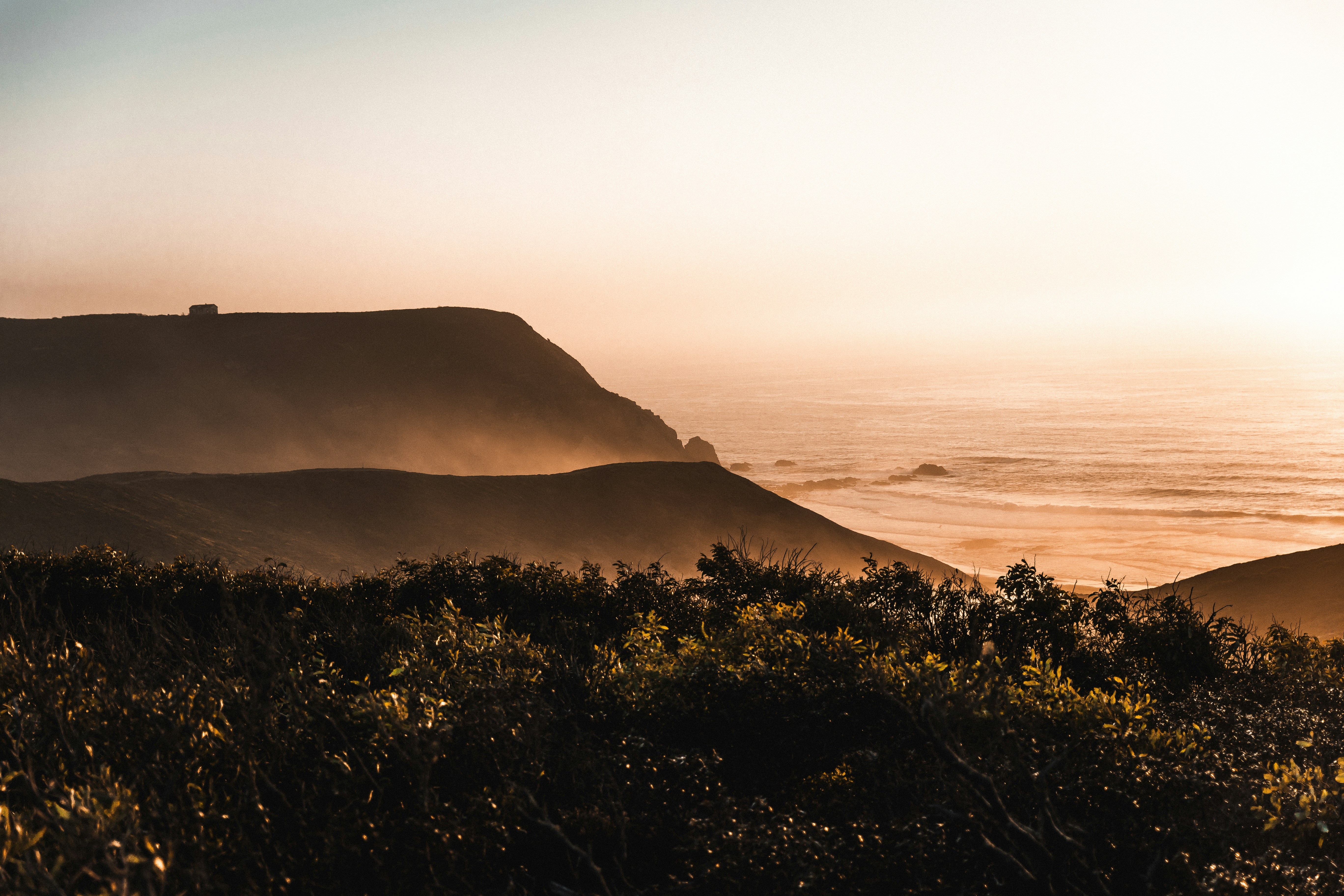 The sun shines on the hills near the ocean