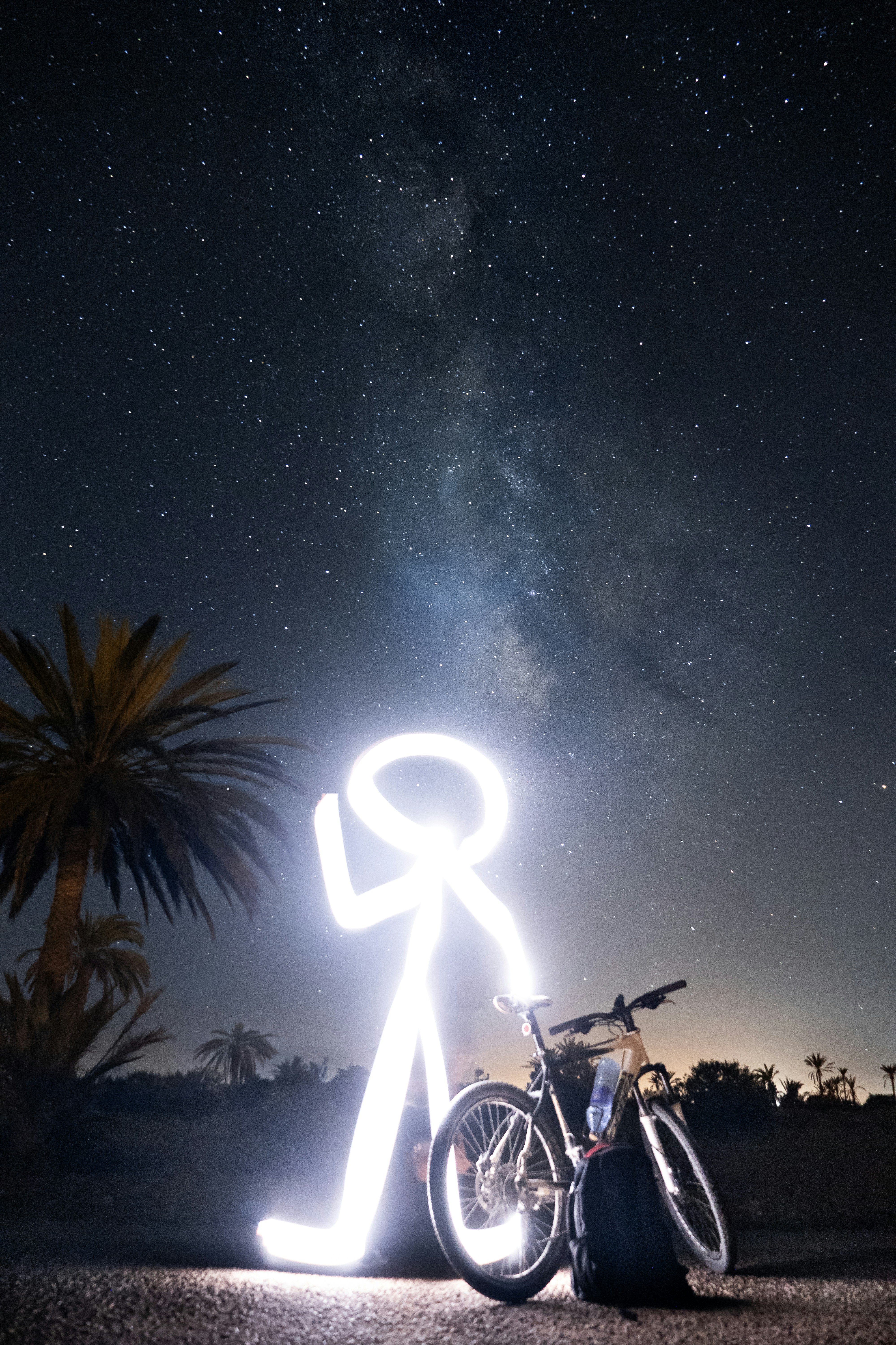 Une personne debout à côté d’un vélo sous un ciel nocturne