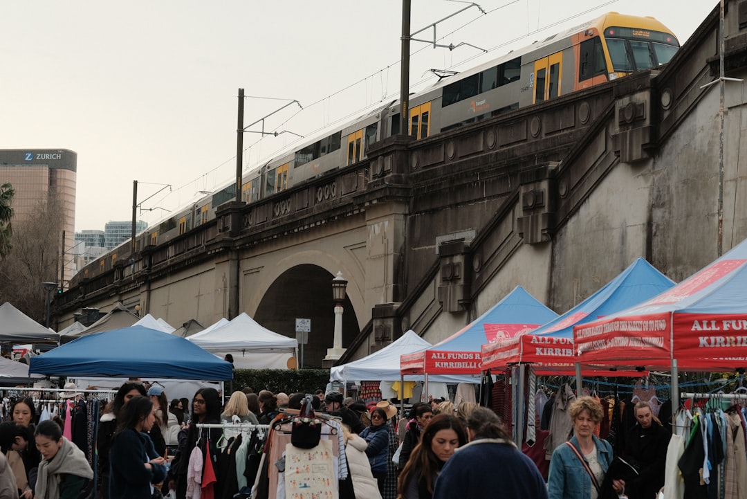 A crowd of people standing around tents with a train in the background,